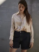 Camisa de seda color beige, de corte amplio y mangas largas con puños. Cierre frontal con botones.