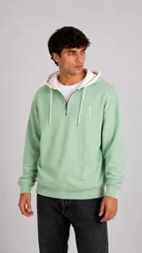 Hoodie de color verde menta con cierre frontal parcial, capucha en contraste color blanco y cordones ajustables. Presenta un pequeño bordado en el pecho y puños acanalados.