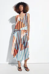 Vestido midi de tirantes con diseño geométrico y de rayas verticales en tonos salmón, celeste, marrón y blanco. Cuenta con escote en V y tirantes cruzados en la espalda.
