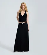 Falda larga de denim color negro, corte evasé con cintura media, bolsillos funcionales, recortes frontales con costura central y bajo desflecado.