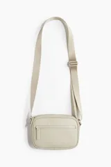 Bandolera color beige con correa larga regulable y bolsillo externo con cierre.