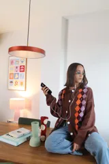 Cardigan de punto negro con diseño de rombos verticales en colores vibrantes como verde, rojo y violeta. Presenta cierre frontal con botones blancos, cuello redondo y mangas largas.