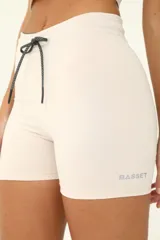 Short deportivo color beige, de tiro alto y corte ajustado. Cuenta con cintura elástica con cordón ajustable reflectivo.