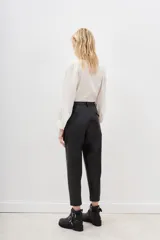 Pantalón estilo capri de efecto cuero negro, con corte holgado y detalles de costuras geométricas en la parte delantera.