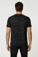 Remera de manga corta con cuello redondo, confeccionada en algodón con estampado botánico de hojas en tonos verdes.