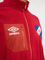 Buzo de micropolar azul con medio cierre frontal, cuello alto y bolsillo con cierre en el pecho. Presenta el logo de Umbro y el escudo del Club Nacional de Football.