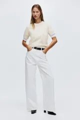 Buzo de punto suave con cuello redondo y mangas cortas. Presenta un ajuste entallado con terminaciones acanaladas en cuello, puños y bajo.