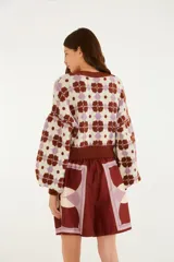 Cardigan de punto con escote en V, cierre frontal con botones y mangas largas abullonadas, con diseño estampado geométrico en tonos marrón, lila y crudo.