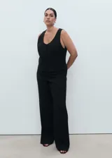 Chaleco negro de corte recto y estilo sastre, con cuello redondo abierto, tirantes anchos y cierre frontal de botones. Cuenta con forro interior completo.