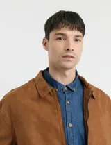 Camisa de jean de manga larga con cuello clásico, cierre frontal con botones y bolsillo tipo parche en el pecho.