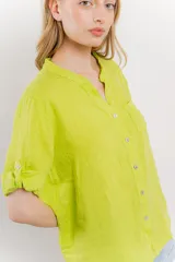 Camisa de lino color verde lima, de calce relajado, con cuello mao, botones al frente y bolsillo en el pecho. Las mangas son cortas y pueden usarse arremangadas.