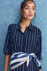 Camisa de calce relajado con cuello clásico, mangas largas con puños elastizados y rayas verticales que aportan un estilo atemporal. Su diseño liviano y versátil cuenta con estampado floral verde sobre fondo de rayas celestes y blancas.