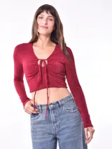 Remera crop top color bordó, de manga larga, con escote en V y detalle de frunce ajustable con cordones en el frente.