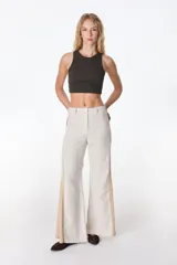 Pantalón de pierna ancha con acabado brillante, confeccionado en lino. Presenta un diseño de tiro medio con cierre de botón y cremallera, bolsillos traseros y etiqueta de marca en la cintura.