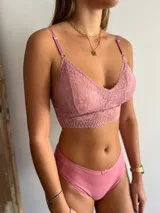Bralette de encaje rosado con diseño triangular, breteles regulables y banda inferior ancha de encaje.