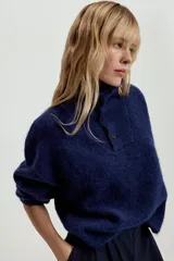 Jersey de punto de textura suave, color azul marino, con cuello perkins y cierre frontal parcial con botones. Presenta mangas largas con diseño holgado.
