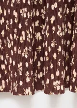 Vestido largo de tejido plisado marrón con estampado floral pequeño, escote en V, manga larga acampanada y diseño evasé.