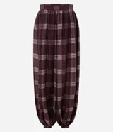 Pantalón estilo balloon de corte amplio y holgado, confeccionado en tejido de viscosa con estampado de cuadros en tonos bordó y blanco. Presenta cintura lisa y fruncido en los tobillos para un mayor volumen.