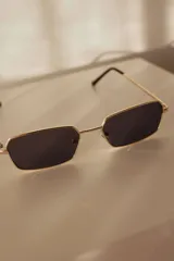 Lentes de sol rectangulares con armazón metálico dorado y lentes marrones con protección UV400.