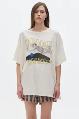 Remera unisex de algodón lavado color beige claro, con cuello redondo y manga corta. Presenta un estampado frontal con texto en dorado que dice "ENFOQUE" y "MOVIMIENTO", y una figura humana en tonos grises y un círculo azul.