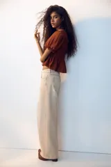 Blusa marrón de lyocell con escote redondo, mangas cortas abullonadas y cuerpo fruncido con detalle de tiras decorativas.