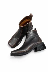 Bota corta de cuero negro con acabado efecto envejecido, punta cuadrada y tacón geométrico. Cuenta con cierre lateral para un calce práctico.