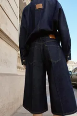 Bermuda de tiro alto confeccionada en denim azul oscuro, con diseño de pernera ancha, cinco bolsillos y cierre frontal con cremallera y botón.