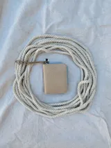 Billetera pequeña de cuero con textura efecto cocodrilo, cierre metálico perimetral y correa de muñeca extraíble. Incluye detalle de moneda metálica decorativa.