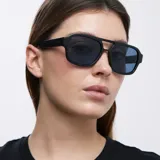 Lentes de sol de aviador oversize, con montura negra y lentes azules polarizadas.