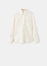 Blusa de diseño recto color crudo con diseño bordado floral, cuello camisero, manga larga con puños anchos abotonados y cierre delantero con botones.