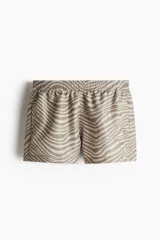 Short de baño con estampado de cebra en tonos beige y marrón, con cintura elástica y cordón de ajuste oculto. Cuenta con bolsillos laterales al bies, tajos en el ruedo y suspensor interior de malla.