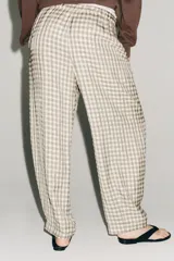 Pantalón de tiro medio con diseño de cuadros vichy en tonos neutros. Presenta pierna ancha, cintura elástica ajustable con cordones, bolsillos laterales y detalle de pinzas en el delantero.