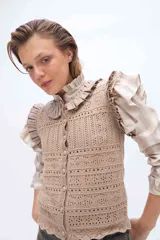 Chaleco tejido de punto color beige con diseño calado, escote redondo y cierre frontal de botones forrados al tono.