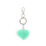 Llavero con dije en forma de corazón confeccionado con pequeñas cuentas esféricas de color turquesa. Incluye una argolla metálica y un gancho de mosquetón plateado.