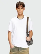 Remera blanca de manga corta con cuello redondo y un gran logo ovalado de Diesel en relieve en el pecho.