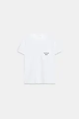 Camiseta blanca de algodón con cuello redondo, manga corta y bolsillo en el pecho que incluye un texto impreso a contraste.