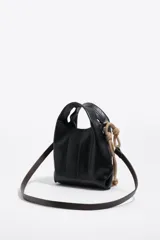 Bolso mini Bimba Y Lola modelo Paper, de cuero negro con diseño suave y asa de mano integrada. Cuenta con detalles de cuerda beige con nudos en el lateral y el logo de la marca impreso en plateado en la parte frontal.