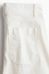 Pantalón de tiro alto confeccionado en lona de algodón de corte recto, con raya marcada al frente y en la espalda, y cierre frontal con dos botones.