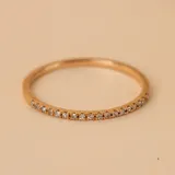 Anillo doble de oro amarillo 18k, compuesto por una banda fina con engaste de pequeños brillantes y otra banda lisa con un brillante central solitario.