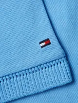 Chomba celeste de piqué de algodón con cuello ribeteado, cartera de cinco botones, logo de Tommy Hilfiger bordado en el pecho y bandera de Tommy Hilfiger bordada en la manga.