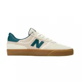 Championes New Balance modelo 272, con diseño de perfil bajo en color crema y detalles en verde petróleo. Presentan una suela de goma color caramelo, cuerpo de lona y gamuza, y el logo característico de la marca en los laterales.