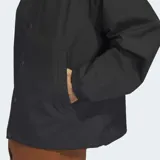 Campera tipo coach de la marca Adidas, color negro, con cuello camisero, cierre frontal de botones a presión y bolsillos laterales. Presenta un pequeño logo bordado en el pecho.