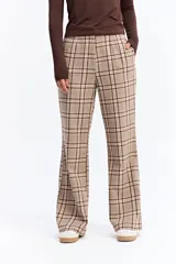 Pantalón de tiro medio con corte recto y leve apertura en el bajo. Presenta un diseño de estampado a cuadros en tonos beige y marrón.