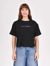 Remera negra de corte cropped con estampado frontal de la frase 'Ma Chérie' en letras plateadas.