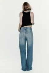 Pantalón de jean con diseño wide leg, de tiro alto y cinco bolsillos, en tono azul desgastado.