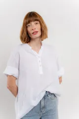 Blusa blanca de lino con escote en V abotonado y mangas cortas arremangadas.