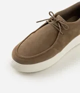 Zapato estilo moc toe para hombre, confeccionado en poliuretano con acabado aterciopelado en color marrón, cierre de cordones y suela gruesa de EVA en color blanco.