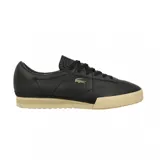 Championes Lacoste modelo Aura, de cuero negro con textura granulada, cordones al tono y suela de goma en color beige. Presenta el logo del cocodrilo metálico en el lateral.