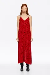 Vestido midi de corte recto con escote en V, tirantes dobles finos y cierre frontal con botones. Presenta un diseño estampado con manchas oscuras sobre fondo rojo.