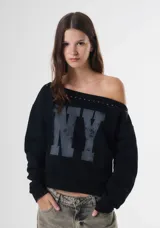 Sweater negro de corte holgado con diseño de hombros caídos, estampado frontal con las letras NY en gris desgastado y detalle de tachas metálicas a lo largo del escote.